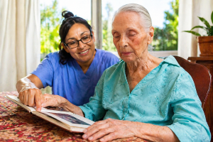 Caregiver assisting a senior woman with a reading activity at Villa Alegría Nursing Home in Costa Rica