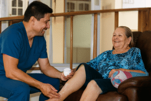A caregiver applying moisturizing cream to an elderly woman’s leg at Villa Alegría Nursing Home in Costa Rica, illustrating compassionate daily skin care and wellness for seniors.
