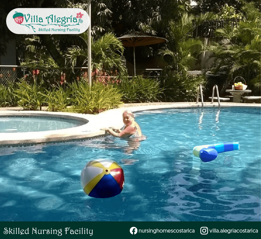 Resident Jhoan enjoying therapeutic swimming in a peaceful outdoor pool at Villa Alegría Nursing Home in Costa Rica