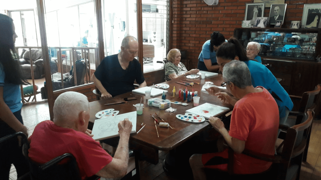 Elderly residents participating in a cognitive stimulation activity with a caregiver at Villa Alegría Nursing Home.