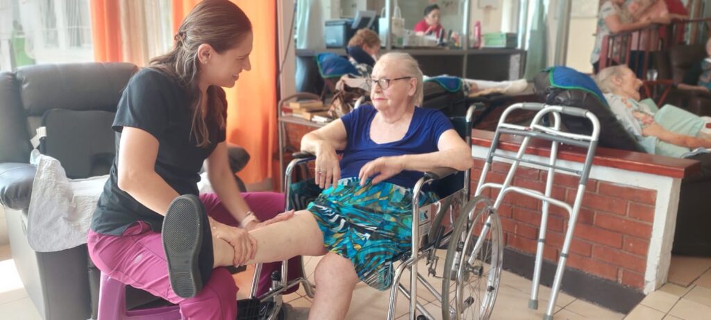 Physical therapist assisting an older adult during rehabilitation at a skilled nursing facility in Costa Rica